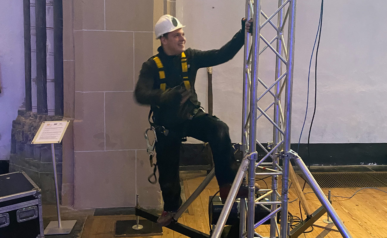 Een van de technici staat gereed om veilig een van onze MPT Truss towers af te monteren op grote hoogte.